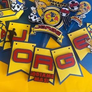 May include: A yellow and blue banner with the letters "JORGE" in red and the words "&iexcl;DI&Aacute;ME M&Aacute;S!" in red. The banner is decorated with soccer balls, a soccer player, and a cartoon bird.