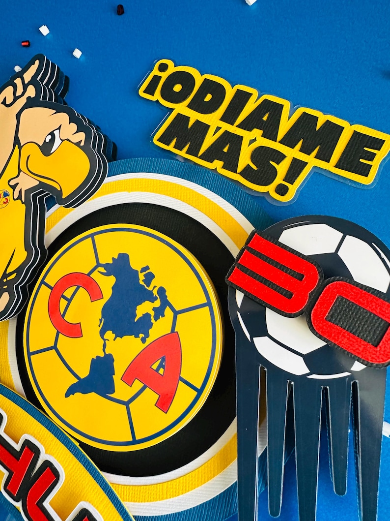 K&ouml;nnte beinhalten: Ein gelbes und schwarzes Fu&szlig;ballteam-Logo mit einer Weltkarte in einem Fu&szlig;ball. Das Logo ist von einem gelben und wei&szlig;en Ring umgeben. Der Text "&iexcl;ODIAME MAS!" befindet sich auf einem gelben Hintergrund mit schwarzen Buchstaben. Ein schwarz-wei&szlig;er Fu&szlig;ball mit einer roten "30" darauf befindet sich auf einem blauen Hintergrund.