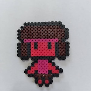 May include: A pixel art character made of colorful beads. The character is a person with brown hair, a red shirt, and pink pants.