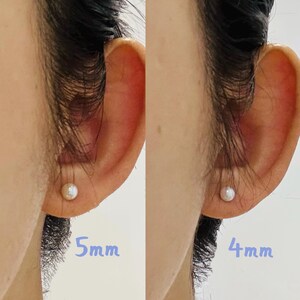 Peut inclure: Gros plan de deux oreilles, chacune orn&eacute;e d'une boucle d'oreille &agrave; clou en perle unique. Une boucle d'oreille est &eacute;tiquet&eacute;e "5mm" et l'autre "4mm", indiquant la taille des perles. Les boucles d'oreilles sont pos&eacute;es sur la peau.