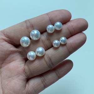 Pode incluir: Uma cole&ccedil;&atilde;o de sete p&eacute;rolas brancas, redondas e soltas, com uma superf&iacute;cie lisa e brilhante. As p&eacute;rolas variam ligeiramente em tamanho e est&atilde;o dispostas em pequenos grupos, destacando o seu brilho iridescente e a sua forma esf&eacute;rica.
