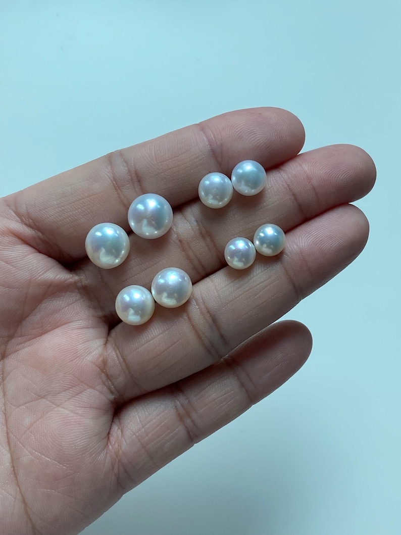 Pode incluir: Uma cole&ccedil;&atilde;o de sete p&eacute;rolas brancas, redondas e soltas, com uma superf&iacute;cie lisa e brilhante. As p&eacute;rolas variam ligeiramente em tamanho e est&atilde;o dispostas em pequenos grupos, destacando o seu brilho iridescente e a sua forma esf&eacute;rica.