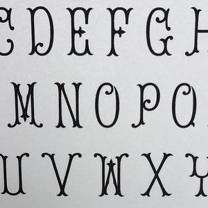 May include: A black and white alphabet with decorative flourishes. The letters are in a traditional font style.