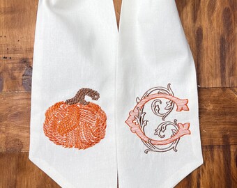 May include: White linen scarf with an embroidered pumpkin and a monogrammed letter C in brown and orange thread.