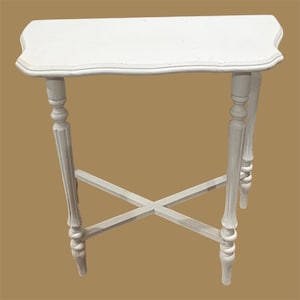 May include: A white, small accent table with a scalloped edge tabletop. The table has four ornate legs with a cross-brace design for stability. The table is painted white and has a vintage aesthetic.