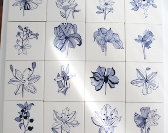 May include: A collection of twenty-four square white ceramic tiles arranged in a grid, each featuring a unique botanical illustration rendered in dark blue ink. The drawings depict various flowers, leaves, and berries with fine line details.