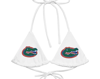May include: White bikini top with a tie-up halter neck and back. Each triangle cup features a green, orange, and blue alligator logo. The bikini top is designed for swimwear.
