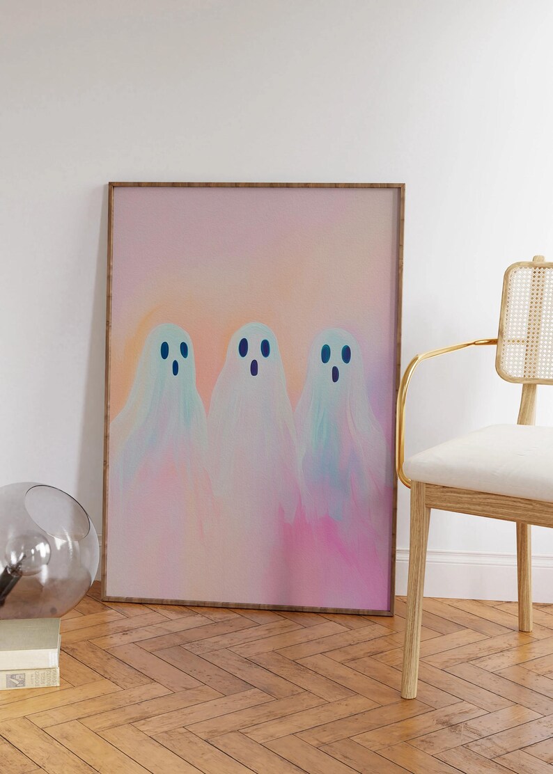 May include: A framed print of three pastel-colored ghosts with blue eyes on a pink and orange background.