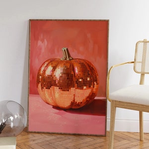 Pu&ograve; includere: Una stampa incorniciata di una grande zucca arancione ricoperta di piastrelle a specchio. La zucca &egrave; appoggiata su una superficie rosa. Lo sfondo &egrave; di un rosa uniforme.