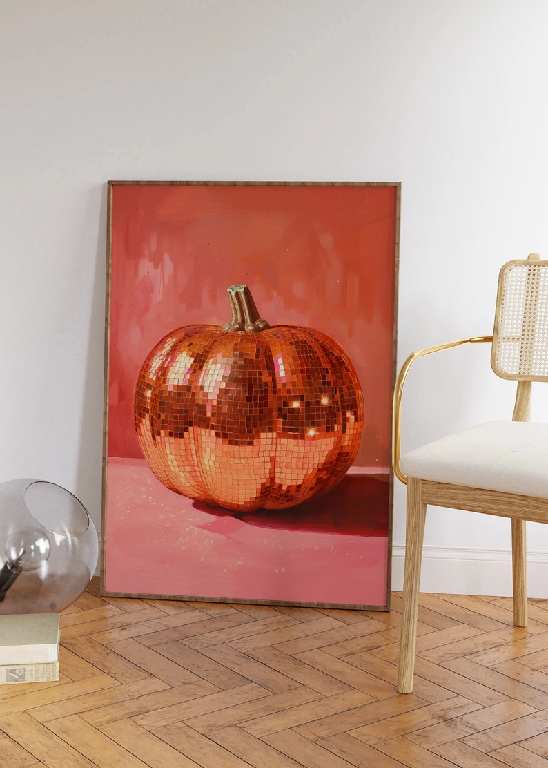 Pu&ograve; includere: Una stampa incorniciata di una grande zucca arancione ricoperta di piastrelle a specchio. La zucca &egrave; appoggiata su una superficie rosa. Lo sfondo &egrave; di un rosa uniforme.