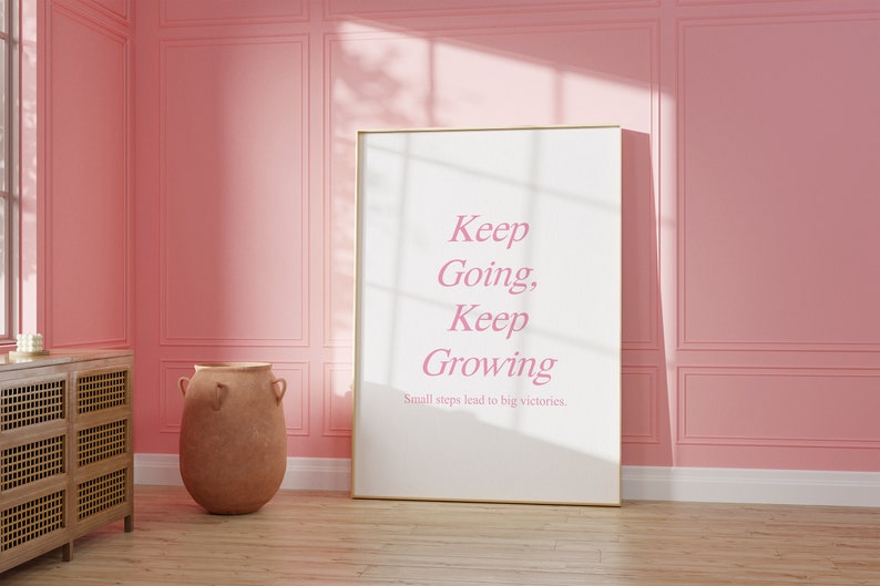 Puede incluir: Un p&oacute;ster motivacional enmarcado con fondo rosa y texto blanco que dice "Keep Going, Keep Growing. Small steps lead to big victories."