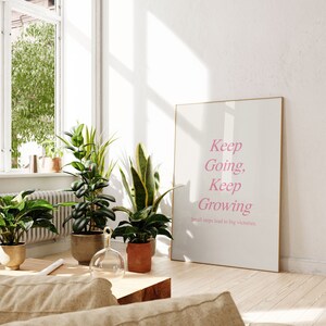Puede incluir: Una impresi&oacute;n enmarcada con el texto "Keep Going, Keep Growing. Small steps lead to big victories." en letras rosas sobre un fondo blanco.