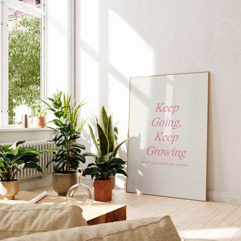 Puede incluir: Una impresi&oacute;n enmarcada con el texto "Keep Going, Keep Growing. Small steps lead to big victories." en letras rosas sobre un fondo blanco.