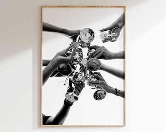 May include: Black and white photograph of multiple hands holding up glasses of champagne, creating a celebratory toast.