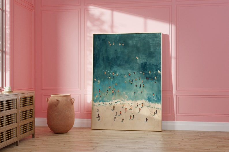 May include: A framed painting of an aerial view of a beach with people swimming and sunbathing in the turquoise water. The beach is white sand and the water is a light blue color.
