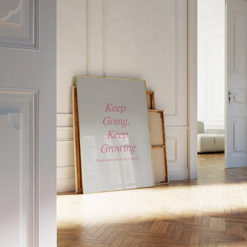 Puede incluir: Un p&oacute;ster motivacional enmarcado con fondo blanco y marco dorado. El texto "Keep Going, Keep Growing" est&aacute; escrito en cursiva rosa. El texto "Small steps lead to big victories" est&aacute; escrito en negro debajo del texto principal.