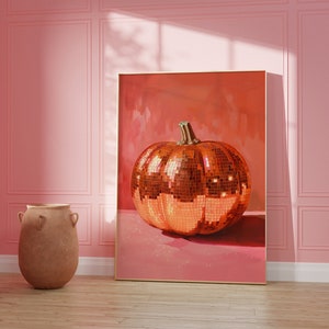 Pu&ograve; includere: Una stampa incorniciata di una zucca a forma di palla da discoteca dorata su sfondo rosa. La zucca &egrave; fatta di piccole piastrelle a specchio.