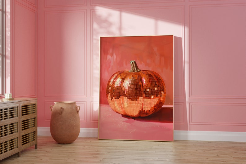 Pu&ograve; includere: Una stampa incorniciata di una zucca a forma di palla da discoteca dorata su sfondo rosa. La zucca &egrave; fatta di piccole piastrelle a specchio.