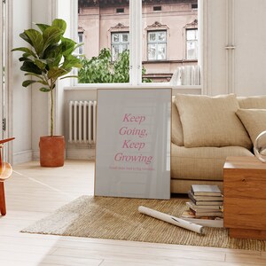 Puede incluir: Un p&oacute;ster motivacional con fondo gris claro y marco dorado. El texto "Keep Going, Keep Growing" est&aacute; escrito en cursiva rosa. El texto "Small steps lead to big victories" est&aacute; escrito en negro, m&aacute;s peque&ntilde;o, debajo del texto principal.