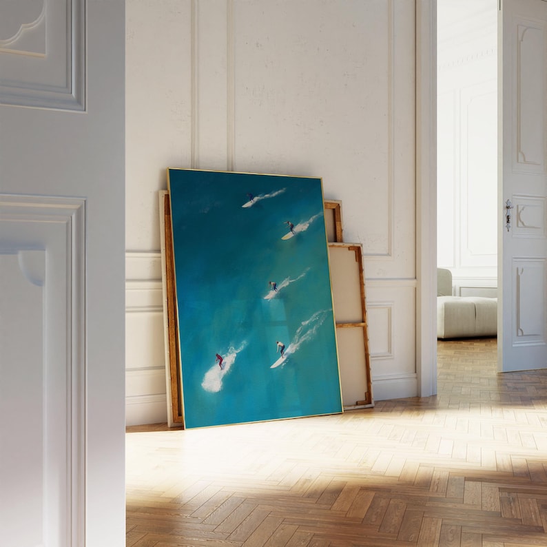Puede incluir: Una pintura enmarcada de un oc&eacute;ano turquesa con cuatro surfistas montando olas. La pintura est&aacute; en un marco dorado y est&aacute; colgada en una pared blanca.