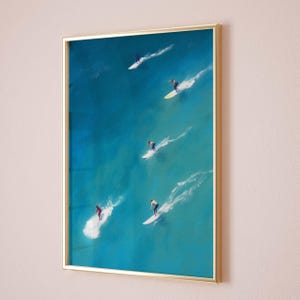 Puede incluir: Una pintura enmarcada de cinco surfistas montando olas en un oc&eacute;ano turquesa. La pintura est&aacute; en un marco dorado.