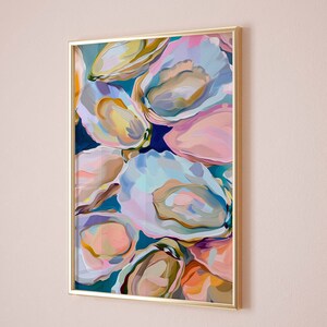 May include: Abstract painting of colorful oyster shells in shades of pink, blue, green, and yellow. The painting is framed in a gold frame.