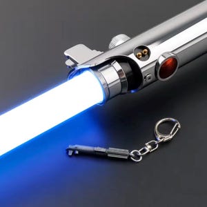 May include: A chrome lightsaber with a bright white blade emitting a blue glow. The hilt has a detailed design with red and black accents. A miniature lightsaber keychain is attached.