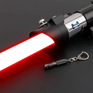 May include: A black lightsaber with a vibrant red blade, radiating a strong glow. A small keychain replica of the lightsaber is also visible. The lightsaber features silver accents and a detailed handle.