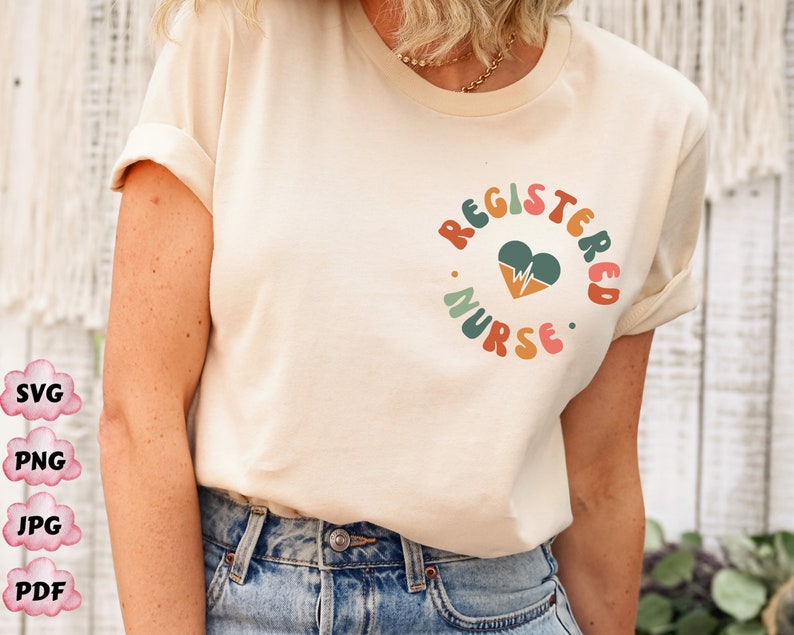 Peut inclure: Un t-shirt blanc avec le texte "REGISTERED NURSE" dans une police r&eacute;tro color&eacute;e. Un c&oelig;ur avec un graphique de battement de c&oelig;ur est au centre du texte.