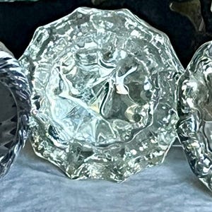 Peut inclure: Trois boutons de porte en verre transparent avec des motifs complexes. Les boutons sont ronds et présentent un design en relief.