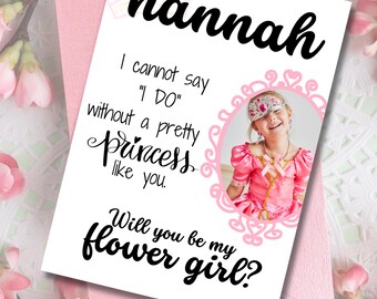 Könnte beinhalten: Eine rosa-weiße Einladungskarte mit dem Namen "hannah" in großer schwarzer Schrift. Die Karte enthält den Text "Ich kann nicht 'JA' sagen ohne eine hübsche Prinzessin wie dich. Willst du mein Blumenmädchen sein?" und ein Foto eines Mädchens in einem Prinzessinnenkostüm.