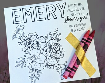 Könnte beinhalten: Weiße Karte mit dem Namen "EMERY", floraler Illustration und dem Text "Roses are red, violets are blue. We need a flower girl and would love if it was you." Zwei rote Buntstifte sind mit goldenem Band an der Karte befestigt.