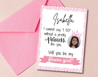 Könnte beinhalten: Eine rosa Einladungskarte mit dem Namen "Isabella" in Schreibschrift, einem Foto eines Mädchens mit Krone und dem Text "I cannot say 'I DO' without a pretty princess like you. Will you be my flower girl?" Ein rosa Umschlag ist im Hintergrund.