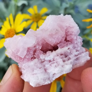 May include: A pink and white crystal cluster with a cave-like opening in the center. The crystal is translucent and has a rough, natural texture.