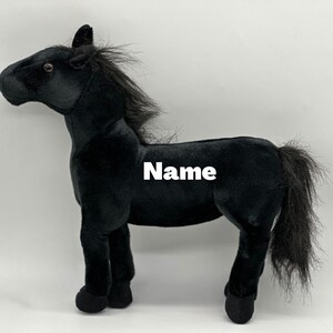 Könnte beinhalten: Ein schwarzes Plüschpferd-Spielzeug mit fließender Mähne und Schweif. Das Spielzeug hat ein realistisches Design mit detaillierten Merkmalen und dem Wort "Name" auf der Seite. Dieses weiche Spielzeug ist für Kinder geeignet.