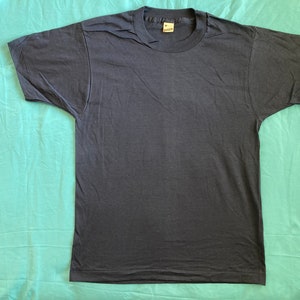 May include: A plain dark blue t-shirt with a white tag that says "Fruit of the Loom" on it.