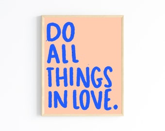 May include: A framed print with a peach background and blue text that reads "Do all things in love."