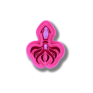 May include: A pink plastic cookie cutter shaped like an octopus. The cutter has a detailed design with tentacles and a head.
