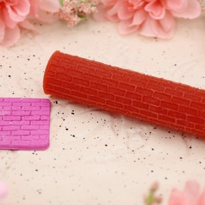 May include: Two silicone molds for baking, one is a long cylinder and the other is a square. Both molds have a brick pattern.
