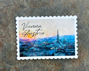 May include: A white rectangular sticker with a postage stamp design featuring a cityscape of Vienna, Austria. The image has a colorful, artistic style with the text "Vienna, Austria" in a script font.