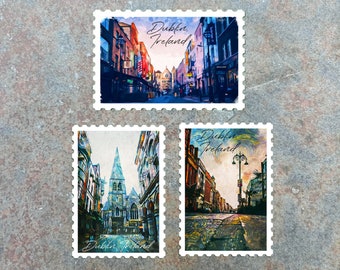 May include: Three postage stamps featuring watercolor paintings of Dublin, Ireland. The stamps depict city streets and architecture, with the text "Dublin, Ireland" in cursive. The stamps are on a textured, gray surface.