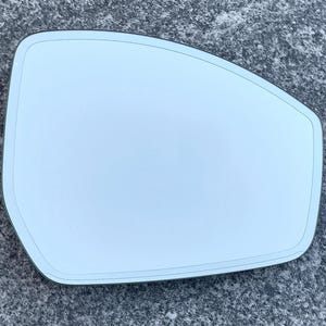 May include: A light blue, slightly curved car side mirror. The mirror has a rectangular shape with rounded corners and a thin black border. The surface is smooth and reflective, suitable for automotive applications.