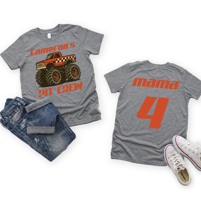 Pu&ograve; includere: Due magliette grigie con testo e grafica arancione. Una maglietta dice "Cameron's PIT CREW" con una grafica di monster truck. L'altra dice "mama 4". Un paio di jeans blu e scarpe da ginnastica bianche sono anche nell'immagine.