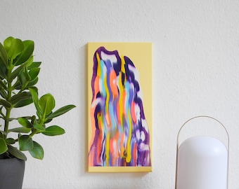 May include: Abstract painting with colorful, fluid shapes on a yellow background. The painting is framed and hanging on a white wall. A potted plant and a white lamp are on a wooden table in front of the painting.