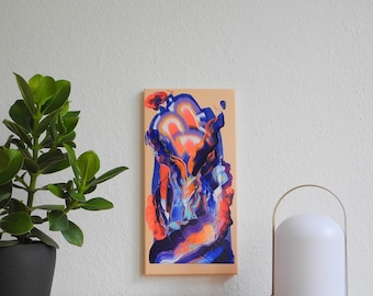 May include: Abstract painting on canvas with swirling blue, orange, and purple colors. The painting is framed and hanging on a white wall above a wooden table.