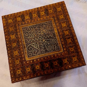 May include: A wooden box with intricate carvings and a geometric design. The box is brown with gold accents.