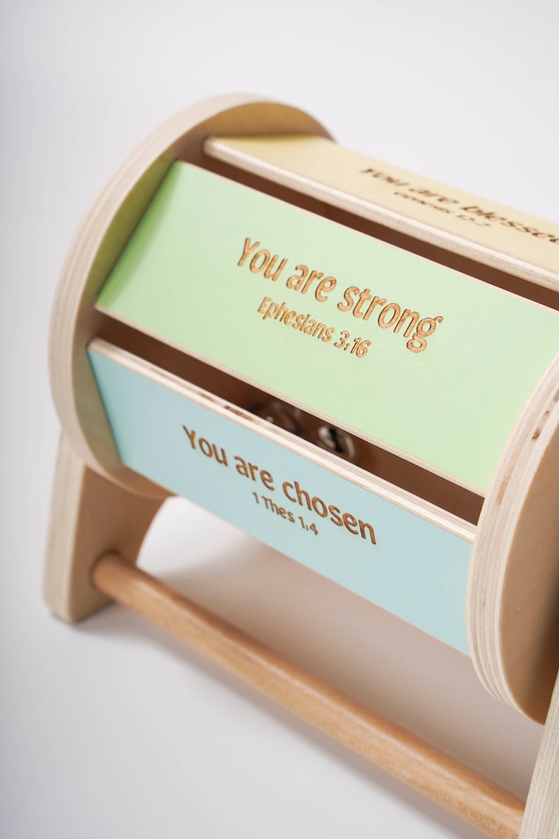 May include: Wooden toy with a handle that rotates to reveal three different inspirational messages: "You are strong, Ephesians 3:16", "You are chosen, 1 Thes 1:4", and "You are blessed, Romans 8:32".
