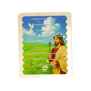 Puede incluir: Un rompecabezas de madera con temática religiosa. El rompecabezas representa a Jesús e incluye el texto del Padre Nuestro. El rompecabezas tiene un cielo azul, hierba verde y una paloma blanca.