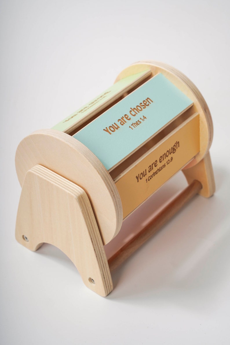 May include: Wooden box with a rotating cylinder that displays inspirational messages. The cylinder has two visible panels, one light blue with the text "You are chosen 1 Thess 1:4" and one orange with the text "You are enough 1 Corinthians 12:9".
