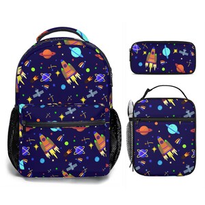 May include: A navy blue backpack, pencil case, and lunch bag set. The space-themed design features rockets, planets, stars, and satellites in orange, yellow, and blue. The backpack has a front pocket and side mesh pocket.